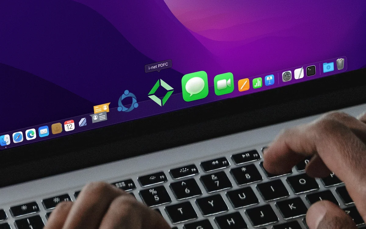 Hands typing on a laptop keyboard with applications visible in the dock, including 'i-net PDFC'.