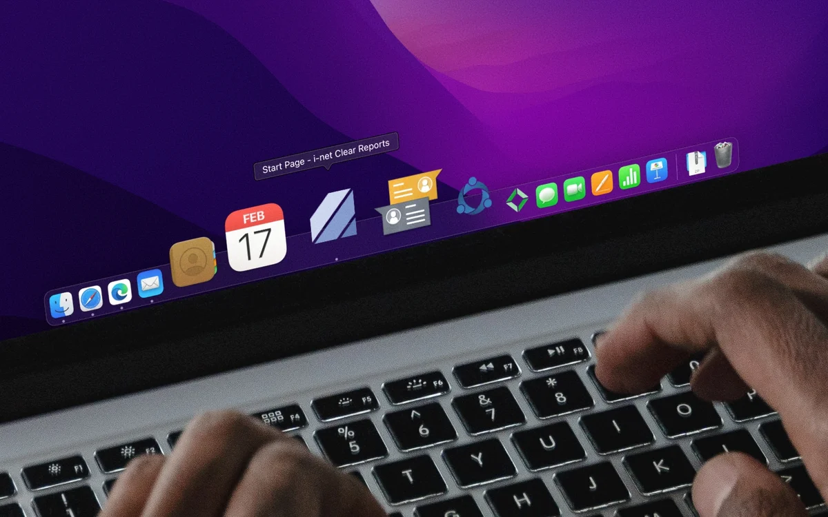 Hands typing on a laptop, desktop showing icons and 'Start Page - i-net Clear Reports'.